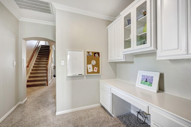 unfurnished office with crown molding, visible vents, built in study area, arched walkways, and light colored carpet