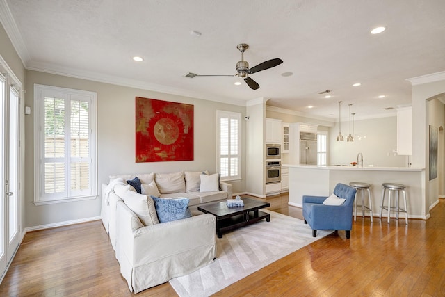 living room featuring plenty of natural light, a ceiling fan, light wood finished floors, and baseboards