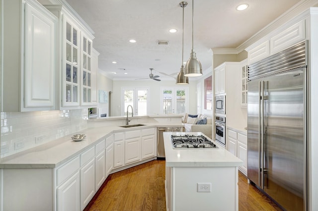kitchen featuring a sink, crown molding, a peninsula, built in appliances, and ceiling fan