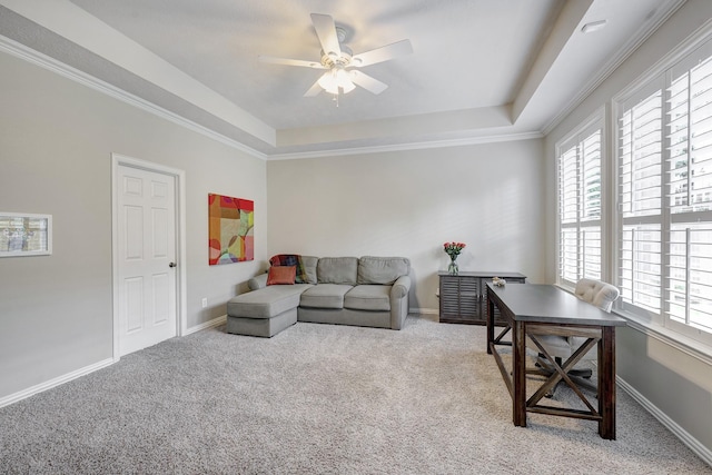 carpeted living room with a tray ceiling, crown molding, baseboards, and ceiling fan