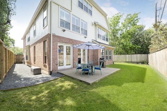 back of house featuring stucco siding, brick siding, a patio area, and a lawn