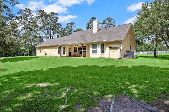 back of house featuring central air condition unit, a patio, a chimney, and a lawn