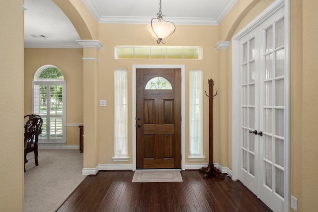 entrance foyer with baseboards, ornamental molding, visible vents, arched walkways, and dark wood-style floors