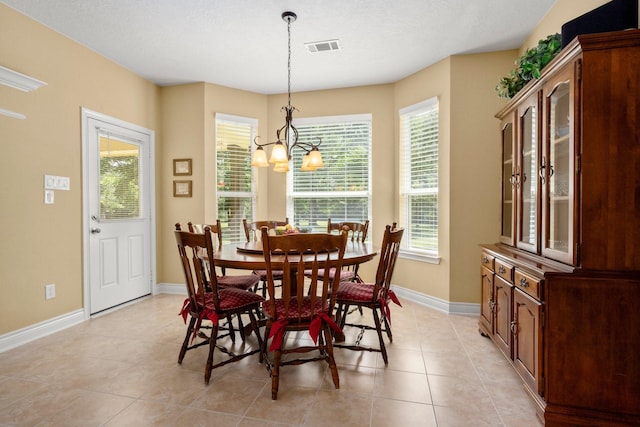 dining room with an inviting chandelier, light tile patterned floors, visible vents, and baseboards