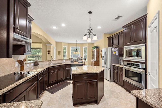 kitchen featuring under cabinet range hood, an inviting chandelier, visible vents, a sink, and appliances with stainless steel finishes