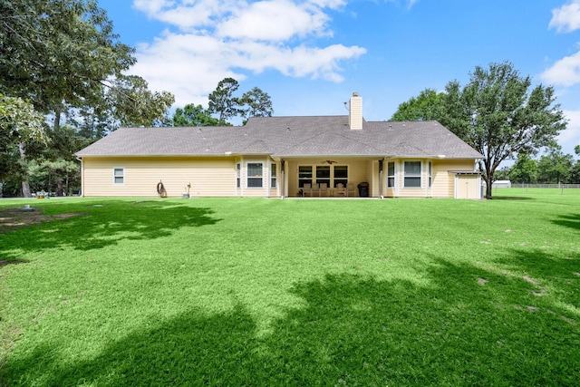 rear view of house featuring a chimney and a lawn