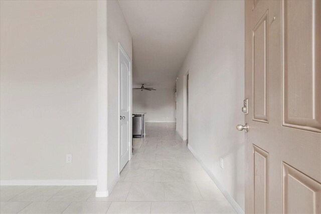 corridor with baseboards and light tile patterned flooring