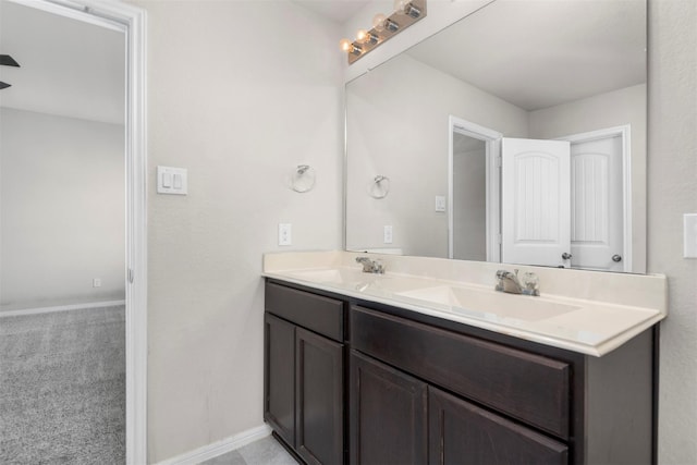 bathroom with double vanity, baseboards, and a sink