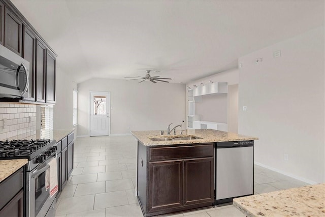 kitchen with stainless steel appliances, a ceiling fan, a sink, baseboards, and a center island with sink