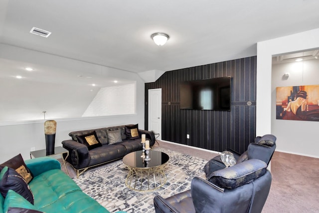 living area with baseboards, an accent wall, visible vents, and carpet