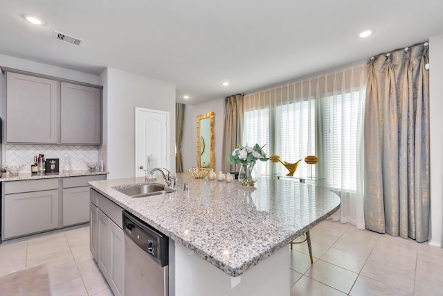 kitchen featuring dishwasher, an island with sink, gray cabinetry, and a sink