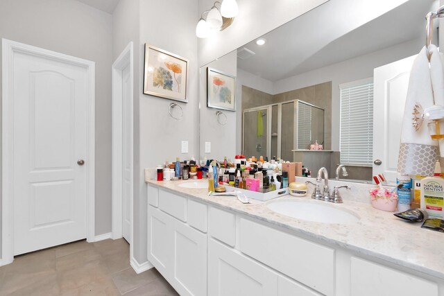 full bathroom with double vanity, a shower stall, tile patterned floors, and a sink
