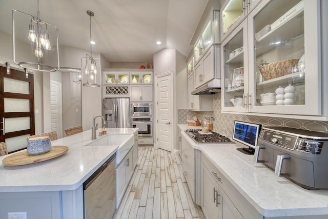 kitchen with a sink, stainless steel appliances, a large island, decorative light fixtures, and backsplash