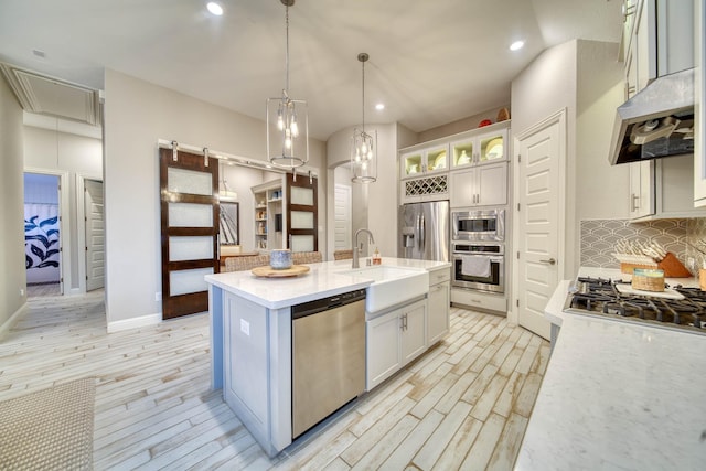 kitchen featuring white cabinetry, decorative backsplash, light wood-style flooring, a sink, and appliances with stainless steel finishes