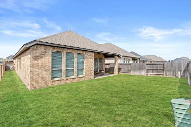 rear view of property featuring a fenced backyard, brick siding, a yard, and roof with shingles