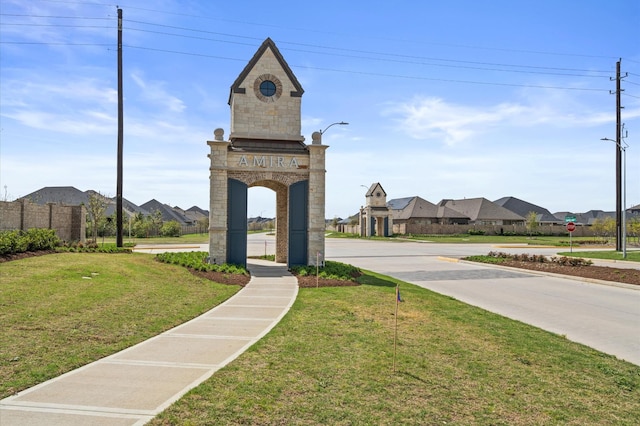 view of community featuring fence, a lawn, and a residential view