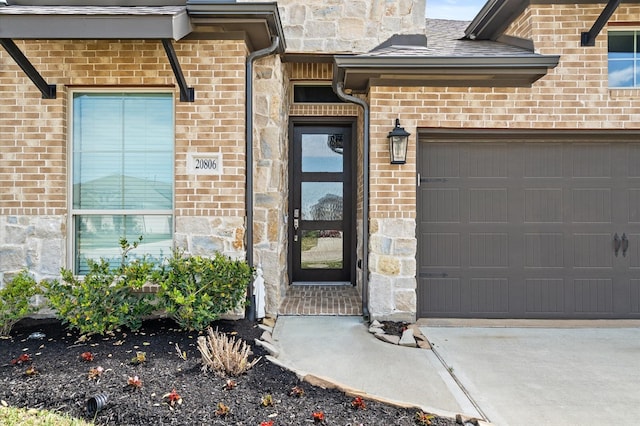 view of exterior entry with stone siding, driveway, brick siding, and a garage