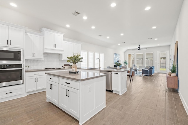 kitchen with a ceiling fan, a sink, appliances with stainless steel finishes, a kitchen island, and recessed lighting