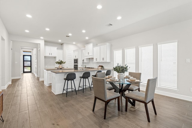 dining area with baseboards, wood finished floors, and visible vents