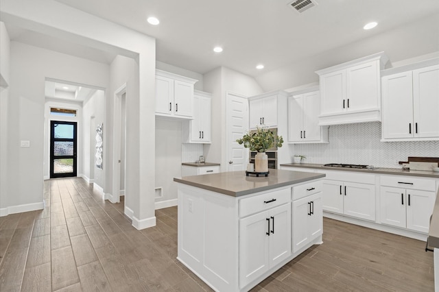 20806 Gray Percheron Ln, Tomball, TX 77377 - kitchen with stainless steel gas cooktop, light wood finished floors, a center island, white cabinetry, and backsplash