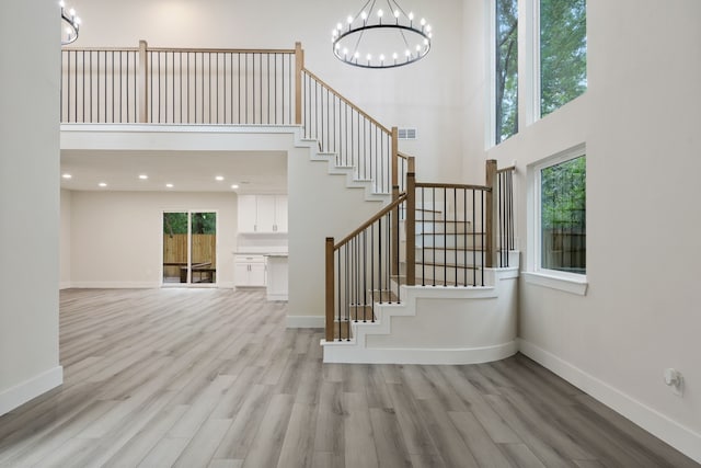 interior space with baseboards, a towering ceiling, wood finished floors, and a chandelier