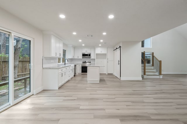 kitchen with a healthy amount of sunlight, appliances with stainless steel finishes, baseboards, and a barn door