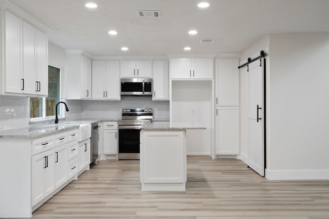 kitchen featuring stainless steel appliances, visible vents, a barn door, and recessed lighting