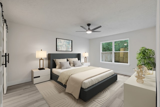 bedroom with a ceiling fan, a textured ceiling, a barn door, baseboards, and light wood-style floors