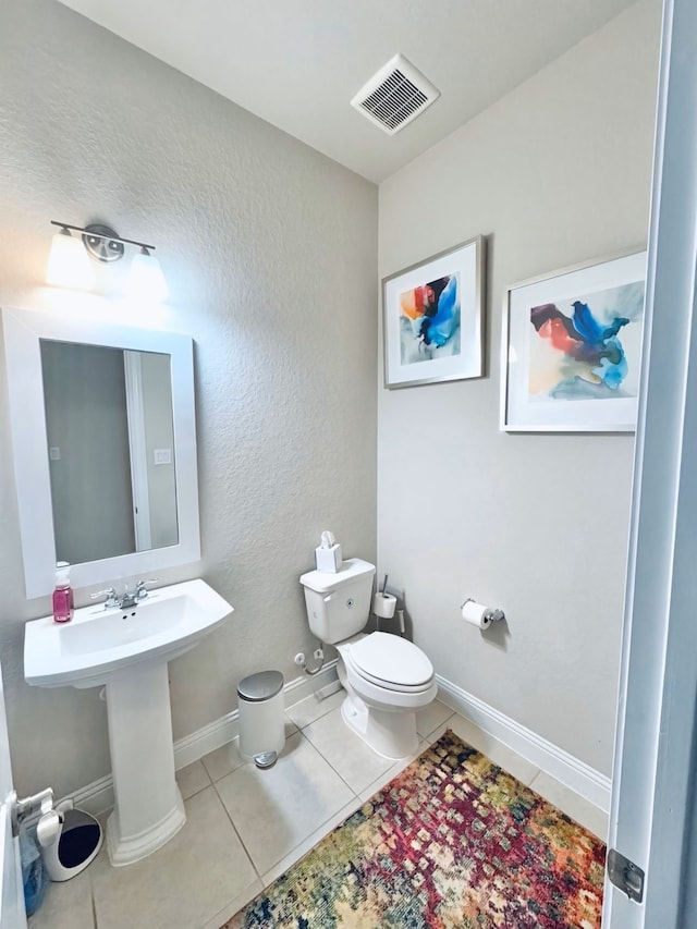 bathroom featuring visible vents, tile patterned flooring, toilet, baseboards, and a sink