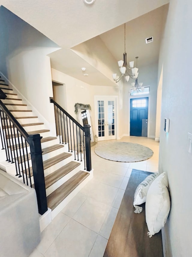 entryway featuring french doors, visible vents, tile patterned flooring, a chandelier, and stairs