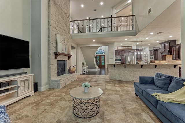 21603 Fairhaven Creek Dr, Cypress, TX 77433 - living area with a towering ceiling, a stone fireplace, baseboards, recessed lighting, and light stone finish flooring
