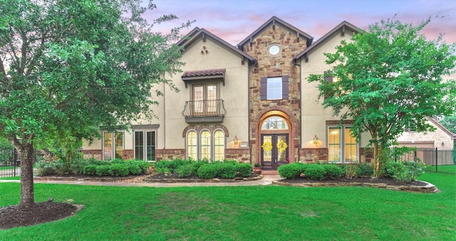 21603 Fairhaven Creek Dr, Cypress, TX 77433 - view of front facade featuring french doors, a balcony, stone siding, stucco siding, and a lawn