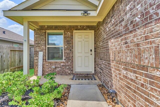 entrance to property with brick siding and fence