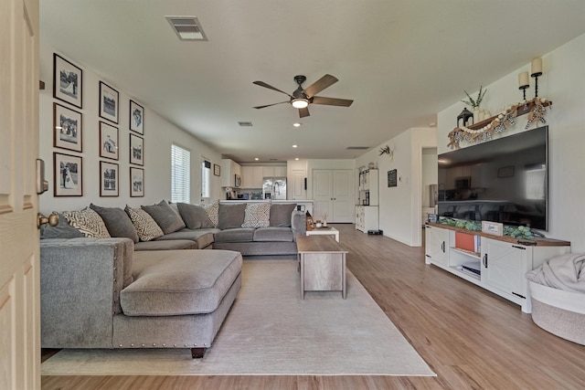 living area featuring wood finished floors, a ceiling fan, and visible vents