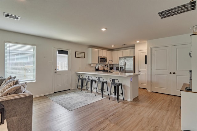 kitchen featuring a peninsula, appliances with stainless steel finishes, a breakfast bar, and visible vents