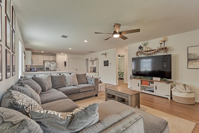 living area with light wood finished floors, a ceiling fan, visible vents, and recessed lighting