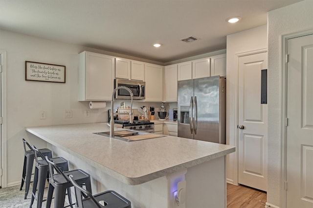 155 Pine Bend Ct, Magnolia, TX 77354 - kitchen with appliances with stainless steel finishes, a peninsula, light countertops, a kitchen bar, and recessed lighting