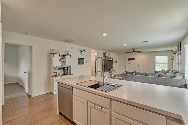 kitchen featuring dishwasher, a ceiling fan, a sink, light wood-type flooring, and white cabinetry