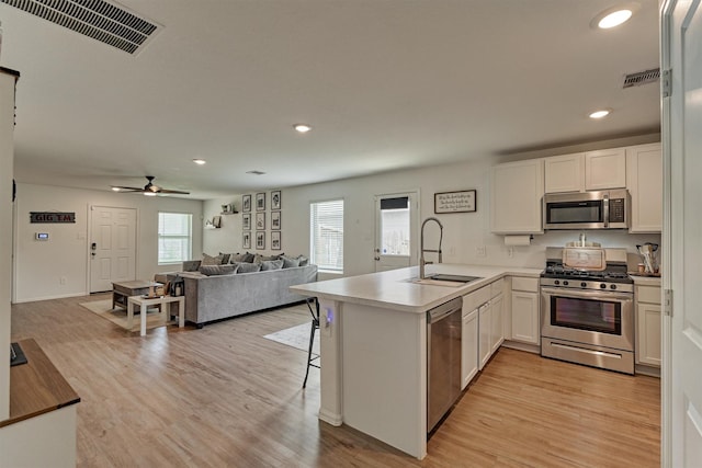 kitchen with stainless steel appliances, a peninsula, visible vents, and a sink