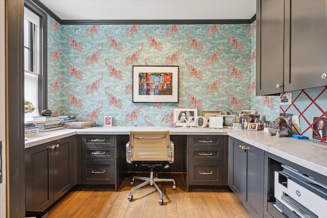 office space with built in desk, wallpapered walls, and light wood-style flooring