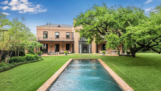 back of house featuring a yard, an outdoor pool, a patio area, and brick siding