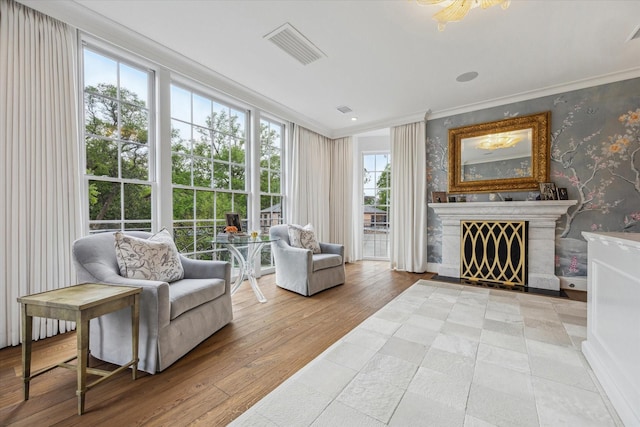 interior space featuring visible vents, wallpapered walls, wood-type flooring, ornamental molding, and a tiled fireplace