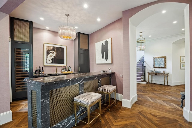 bar featuring beverage cooler, a chandelier, arched walkways, bar area, and stairs