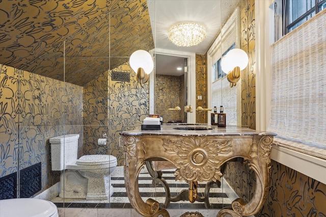 bathroom with a sink, a chandelier, tile patterned floors, toilet, and wallpapered walls