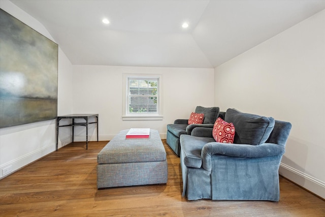 living area with baseboards, wood finished floors, and vaulted ceiling