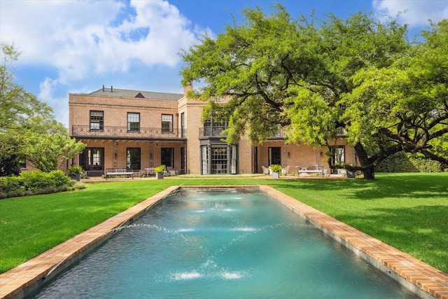 back of house with an outdoor pool, a yard, and brick siding