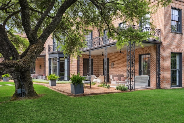 back of property with brick siding, a lawn, and a balcony