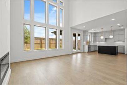 401 Wild Thicket Dr, Katy, TX 77493 - unfurnished living room featuring light wood-style flooring and a towering ceiling