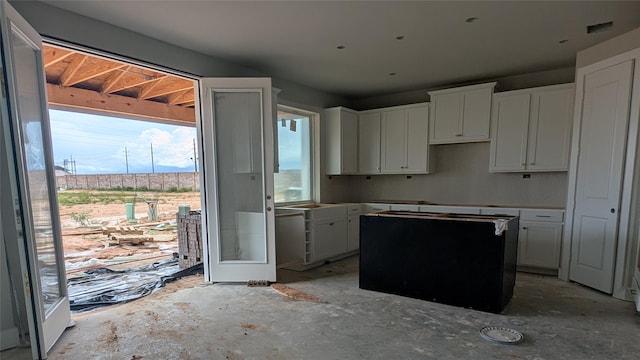401 Wild Thicket Dr, Katy, TX 77493 - kitchen featuring a kitchen island, concrete flooring, and white cabinetry