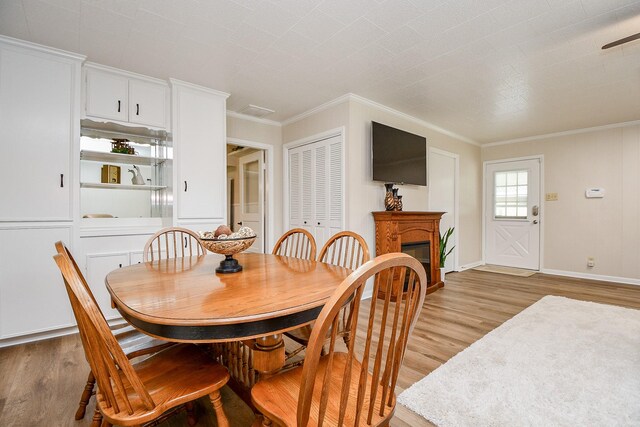 3339 Terry St, Needville, TX 77461 - dining room featuring crown molding, baseboards, a glass covered fireplace, and light wood finished floors